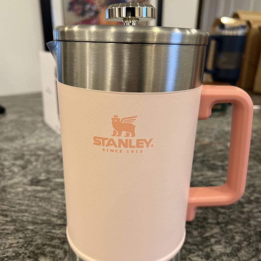 Pink stanley french press sitting on a granite counter