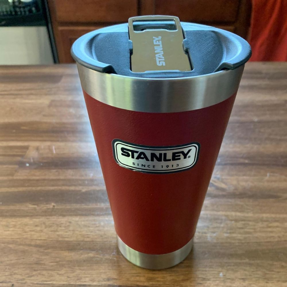 Red Stanley Stay Chill Beer Pint sitting on wooden table.