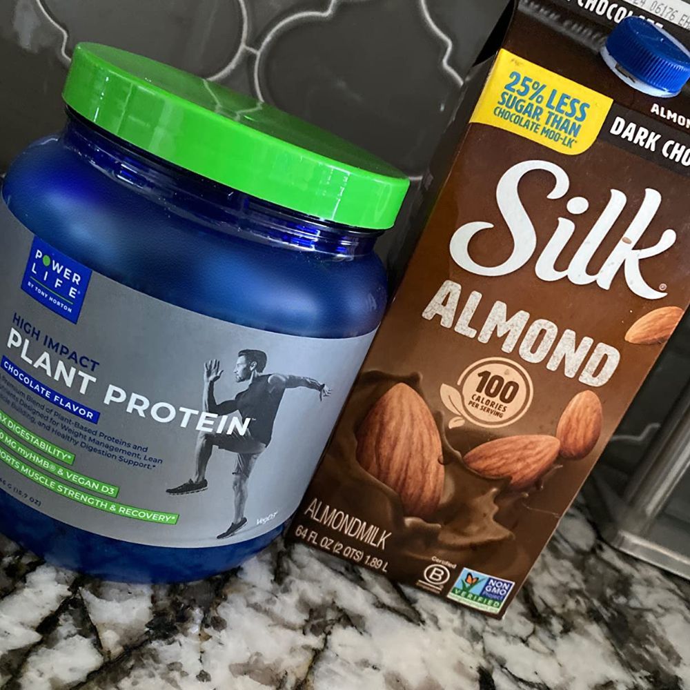 Jar of Power Life high impact plant protein next to Silk chocolate almond milk.