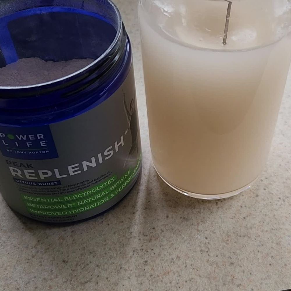 Open jar of peak replenish next to glass of water mixed with peak replenish.